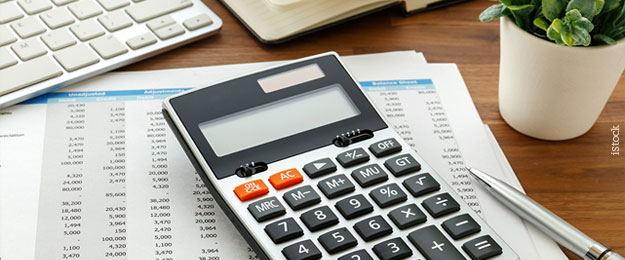 Educação financeira - Mesa com teclado de computador, calculadora, planilha, caneta e vaso de planta